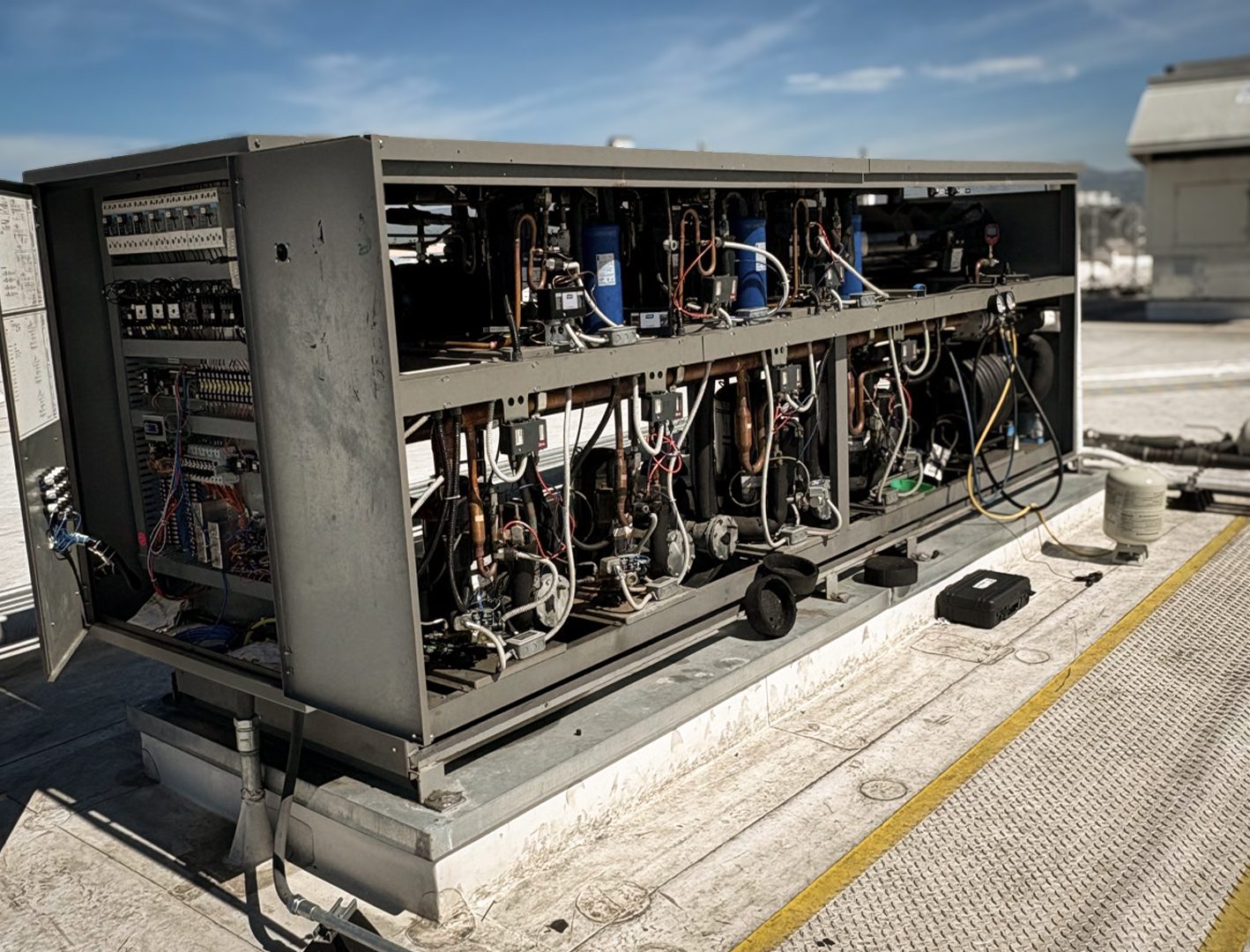 Commercial rooftop refrigeration unit with open panel showing internal components during servicing