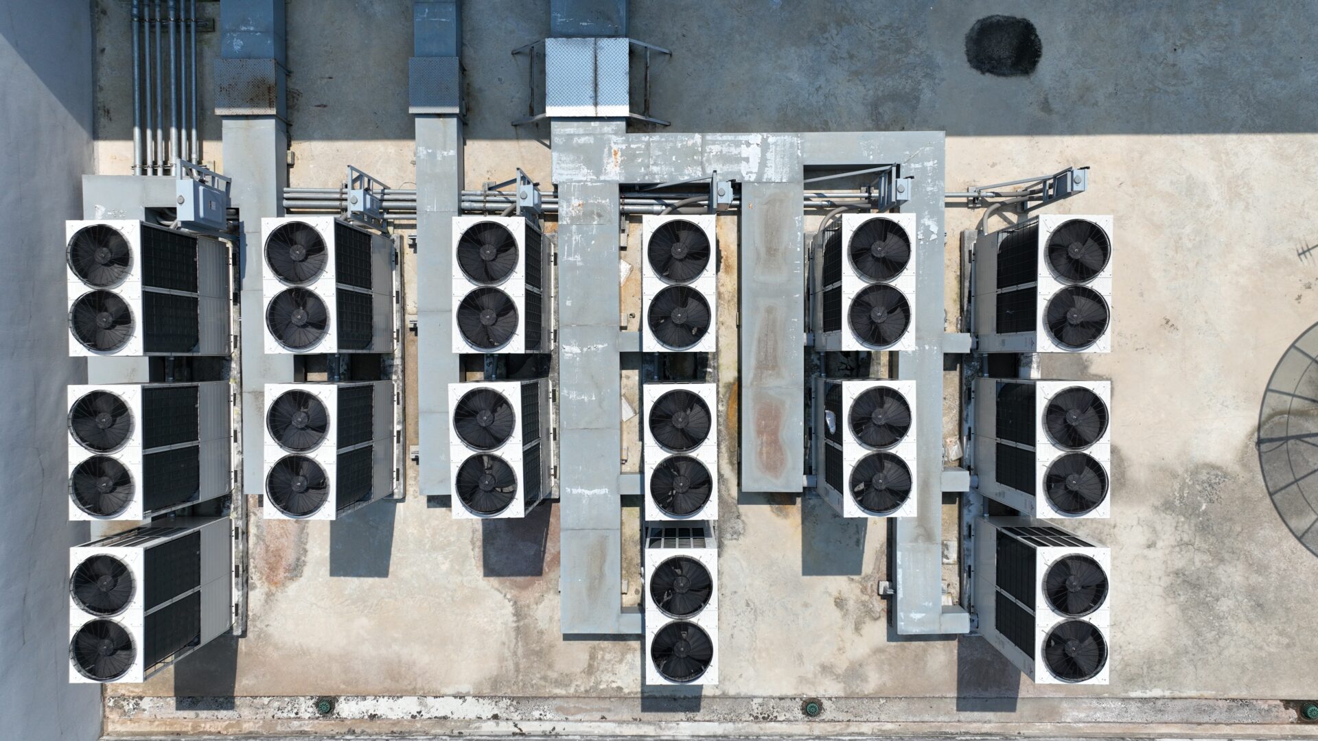 Aerial view of multiple commercial rooftop HVAC and refrigeration condenser units installed on an industrial building