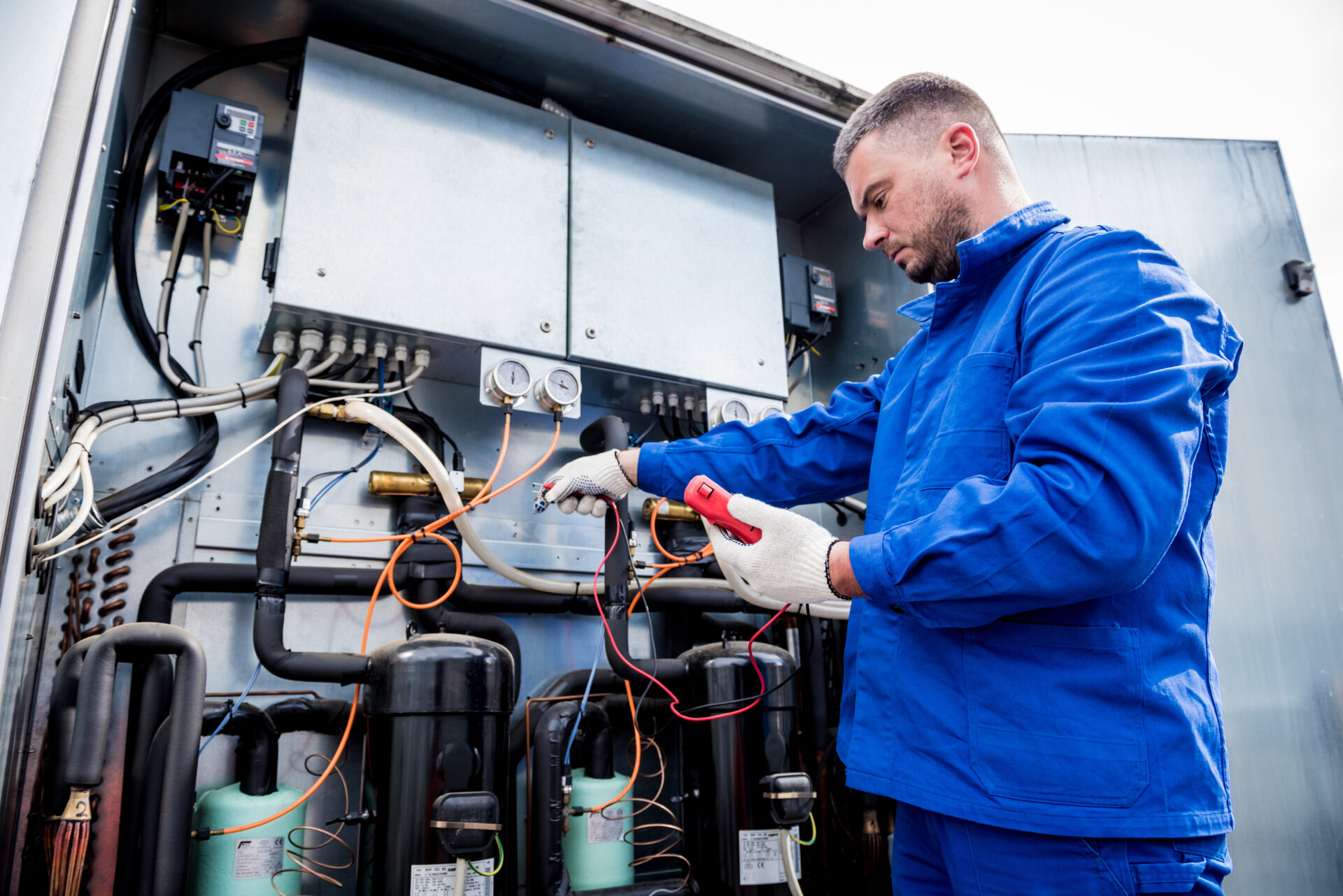Commercial refrigeration technician performing diagnostics and repair on industrial refrigeration system
